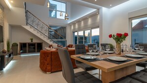 A modern dining area with a wooden table set for four, surrounded by black upholstered chairs. A staircase with a metal railing leads to an upper level. - Sun Stone in Trogir With 4 Bedrooms and 4 Bathrooms (Trogir)