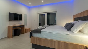 A modern bedroom with a wooden bed, a desk, a television, and a window with blinds. - Sun Stone in Trogir With 4 Bedrooms and 4 Bathrooms (Trogir)