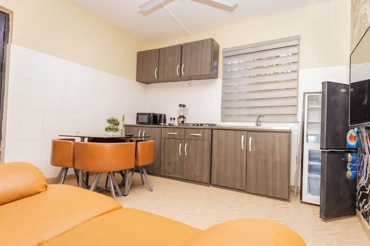 A compact kitchen with a dining area, a refrigerator, and a microwave.
