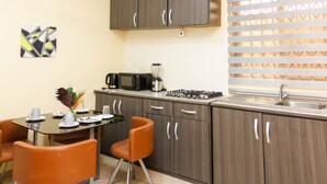 Cocina compacta con comedor, equipada con estufa a gas, microondas y cafetera.