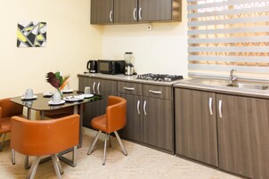 Cozinha compacta com área de jantar, equipada com fogão a gás, micro-ondas e cafeteira.