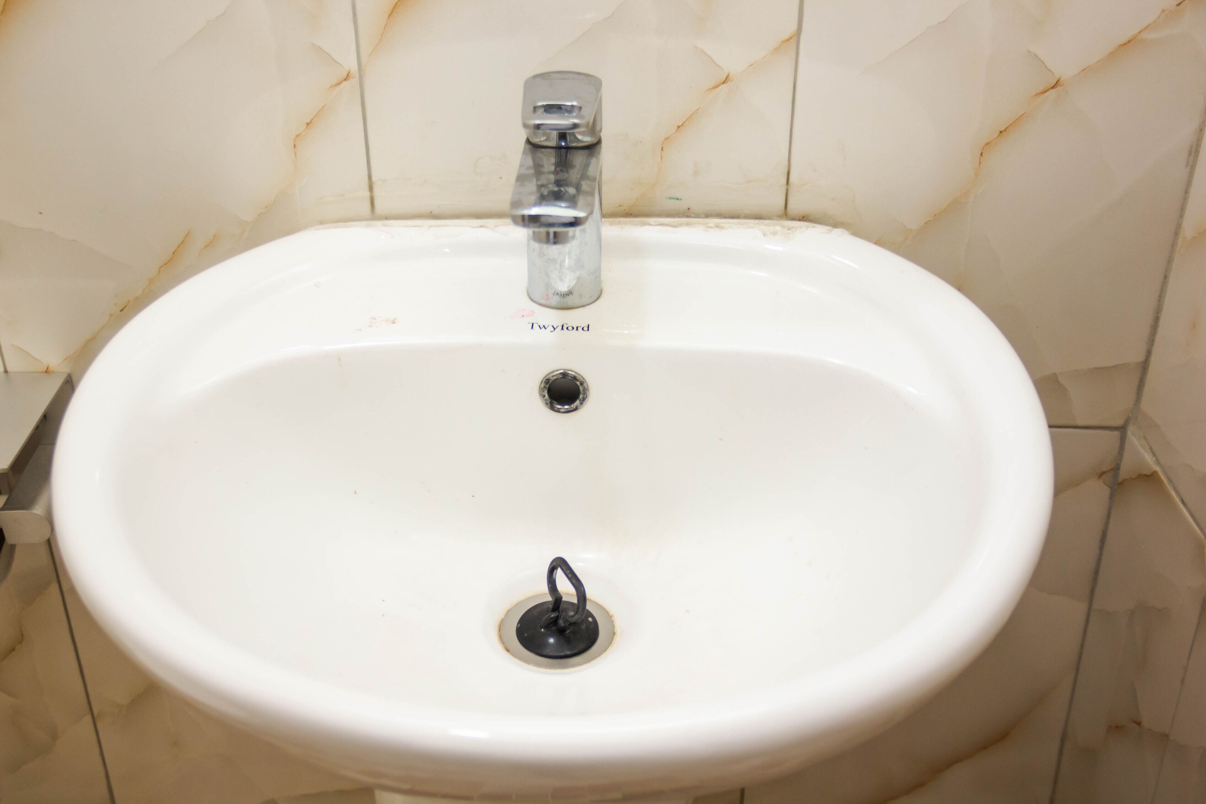 Un lavamanos blanco con un solo grifo y desagüe.