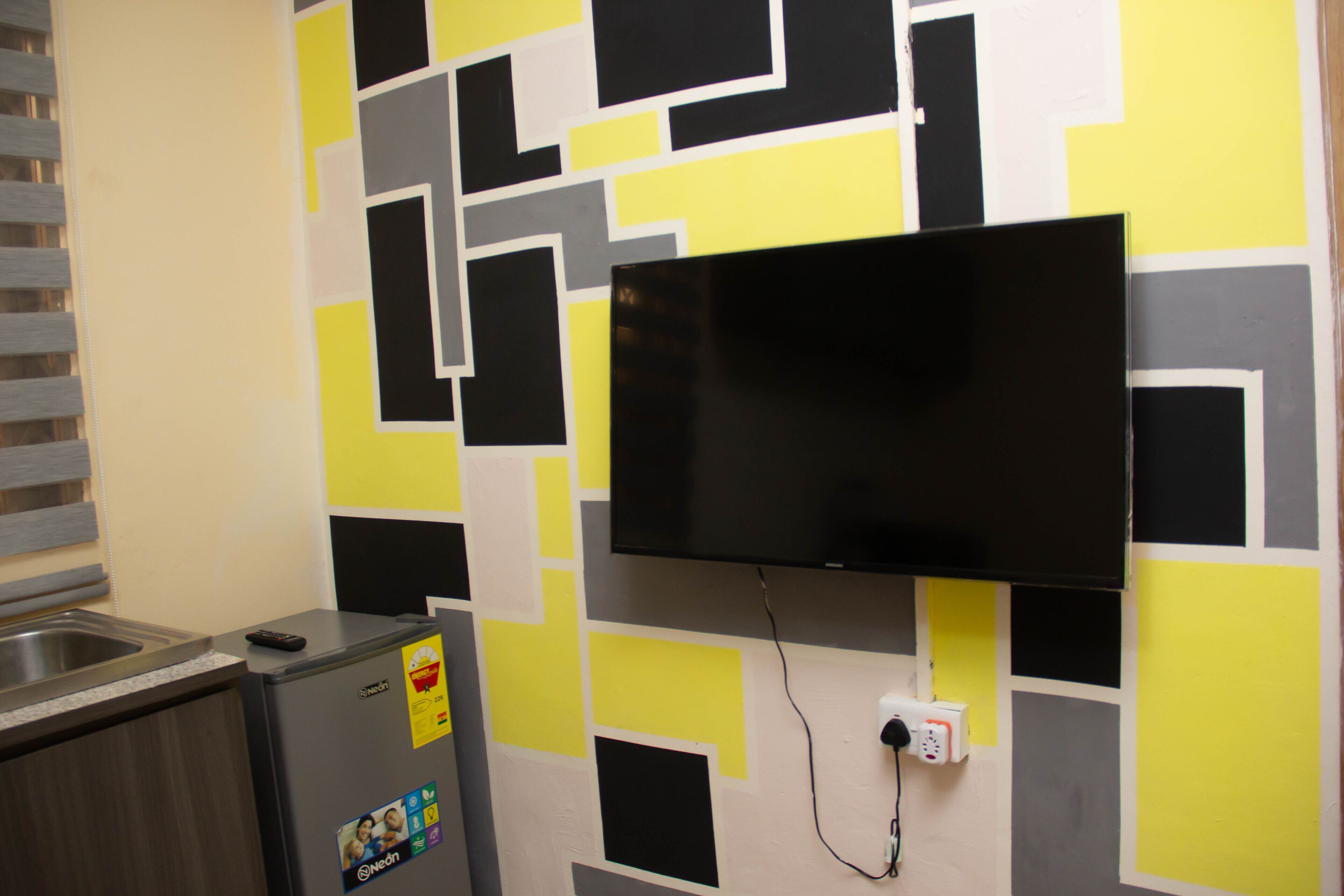 A kitchen with a built-in refrigerator, a microwave, and a flat-screen TV mounted on the wall.