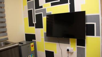 A kitchen with a built-in refrigerator, a microwave, and a flat-screen TV mounted on the wall.