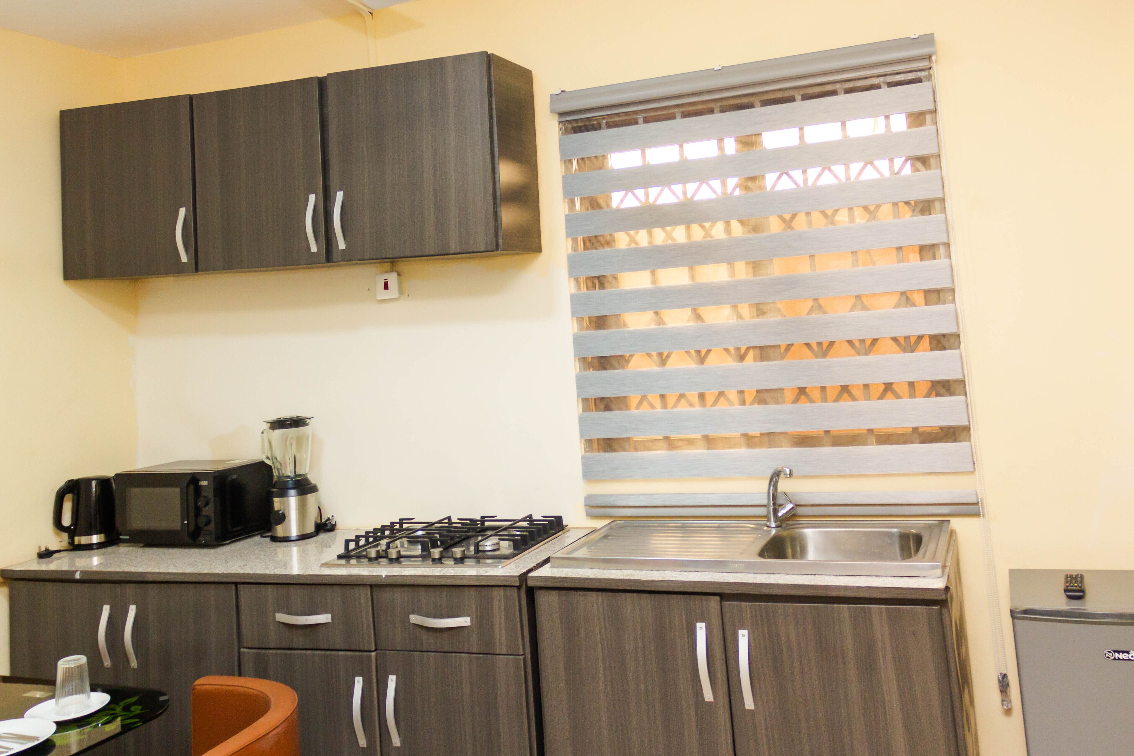 A compact kitchen with dark wood cabinets, a built-in microwave, a gas stove, and a sink.