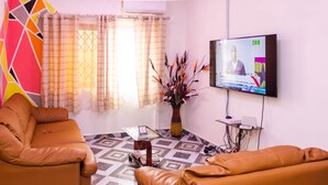 Una sala de estar con televisión, una mesa de centro y dos sofás de cuero.