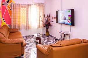 Uma sala de estar com televisão, mesa de centro e dois sofás de couro.