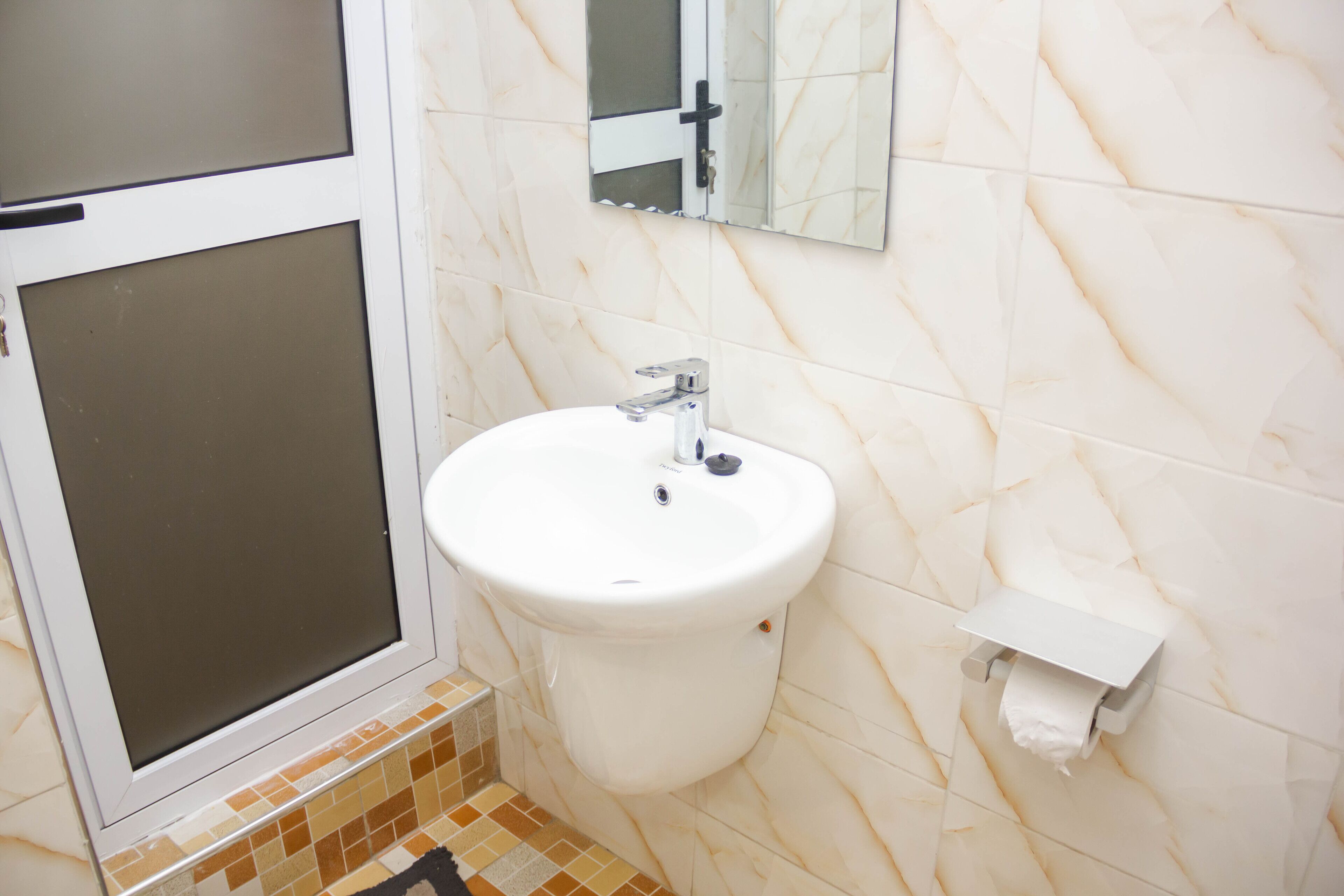A bathroom with a toilet, sink, and a mirror.