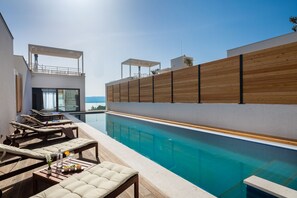 A modern poolside area with lounge chairs and a wooden deck. - Bura in Maru i i With 3 Bedrooms and 3 Bathrooms (Omis)