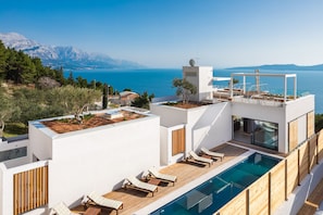A modern rooftop pool area with lounge chairs, a swimming pool, and a view of the sea and mountains. - Bura in Maru i i With 3 Bedrooms and 3 Bathrooms (Omis)