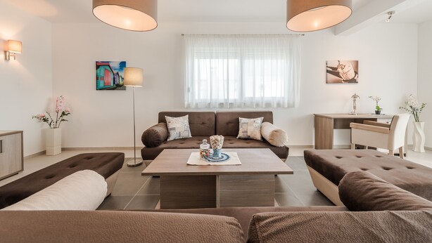 A modern living room with a brown sofa set, a coffee table, and two pendant lights. - Dalmacija III in Suko an (Sukosan)