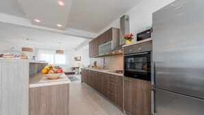 A modern kitchen with wooden cabinets, a stainless steel refrigerator, and a fruit bowl on the counter. - Dalmacija III in Suko an (Sukosan)