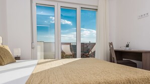 A hotel room with a large bed, a desk, and a view of the sky through a sliding door. - Dalmacija III in Suko an (Sukosan)