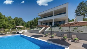 A modern pool area with a clear blue pool, sun loungers, and umbrellas. - Althea in Ru i i With 4 Bedrooms and 4 Bathrooms (Sveta Nedelja)
