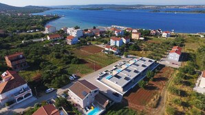 Vista aerea di una zona residenziale costiera con case, un porto turistico e un'ampia distesa d'acqua.