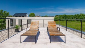 Una terraza en la azotea con dos sillones de madera y un panel solar.