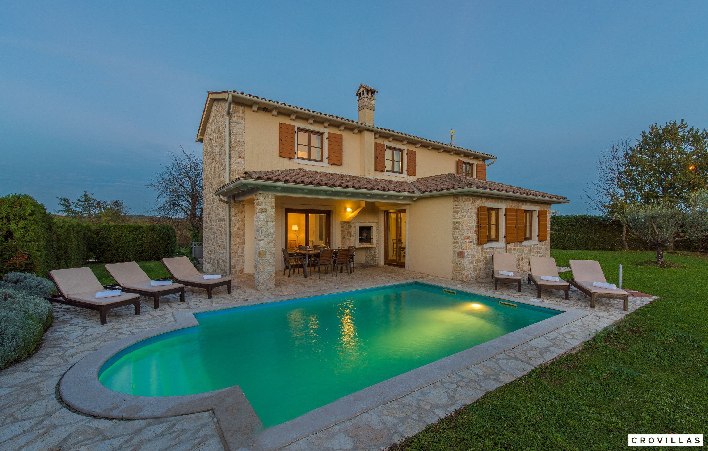 A two-story house with a swimming pool, outdoor seating, and a patio area.