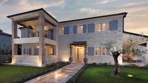 A two-story stone house with a balcony, a covered entrance, and a well-lit garden. - Zoe in Ladi i With 4 Bedrooms and 4 Bathrooms (Kanfanar)