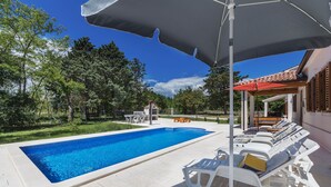 A swimming pool with lounge chairs and umbrellas, surrounded by trees and a building. - Ana Labin in Labin With 6 Bedrooms and 1 Bathrooms (Labin)