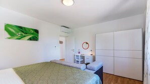 A bedroom with a bed, a desk, a wardrobe, and a green wall art piece. - Ana Labin in Labin With 6 Bedrooms and 1 Bathrooms (Labin)