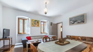 Un espace repas comprenant une table ronde, des chaises et un téléviseur posé sur un meuble.