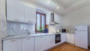 Une cuisine moderne avec des meubles blancs, un four encastré, un four à micro-ondes et un réfrigérateur.