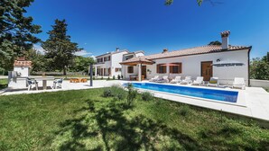 Une maison à deux étages avec une piscine, un espace salon extérieur et un jardin.