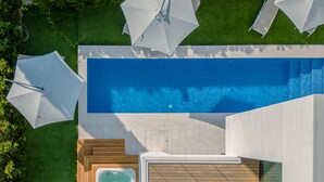 An aerial view of a modern outdoor pool area with a hot tub, wooden deck, and umbrellas. - Calma II in Starigrad (Starigrad)