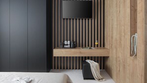 A modern hotel room with a large bed, a wooden desk with a flat-screen TV, a coffee maker, and a small seating area. - Calma II in Starigrad (Starigrad)