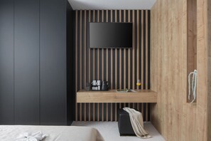 A modern hotel room with a large bed, a wooden desk with a flat-screen TV, a coffee maker, and a small seating area. - Calma II in Starigrad (Starigrad)