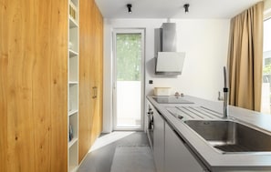 Une cuisine moderne avec des meubles en bois, un évier en acier inoxydable et une fenêtre avec des rideaux.