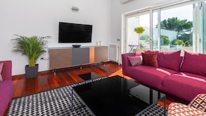 A modern living room with a flat-screen TV, a sofa, a coffee table, and a large window offering a view of the outdoors. - Andreja in Punat With 6 Bedrooms and 6 Bathrooms (Punat)