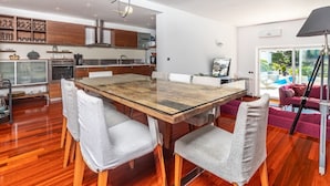 A modern kitchen with wooden cabinets, a large dining table, and a bright pendant light. - Andreja in Punat With 6 Bedrooms and 6 Bathrooms (Punat)