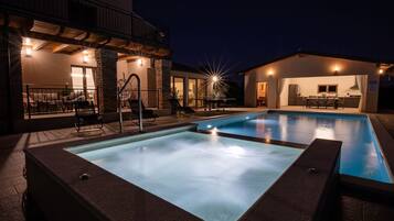 Una piscina con hidromasaje, mobiliario de exterior y un patio cubierto.