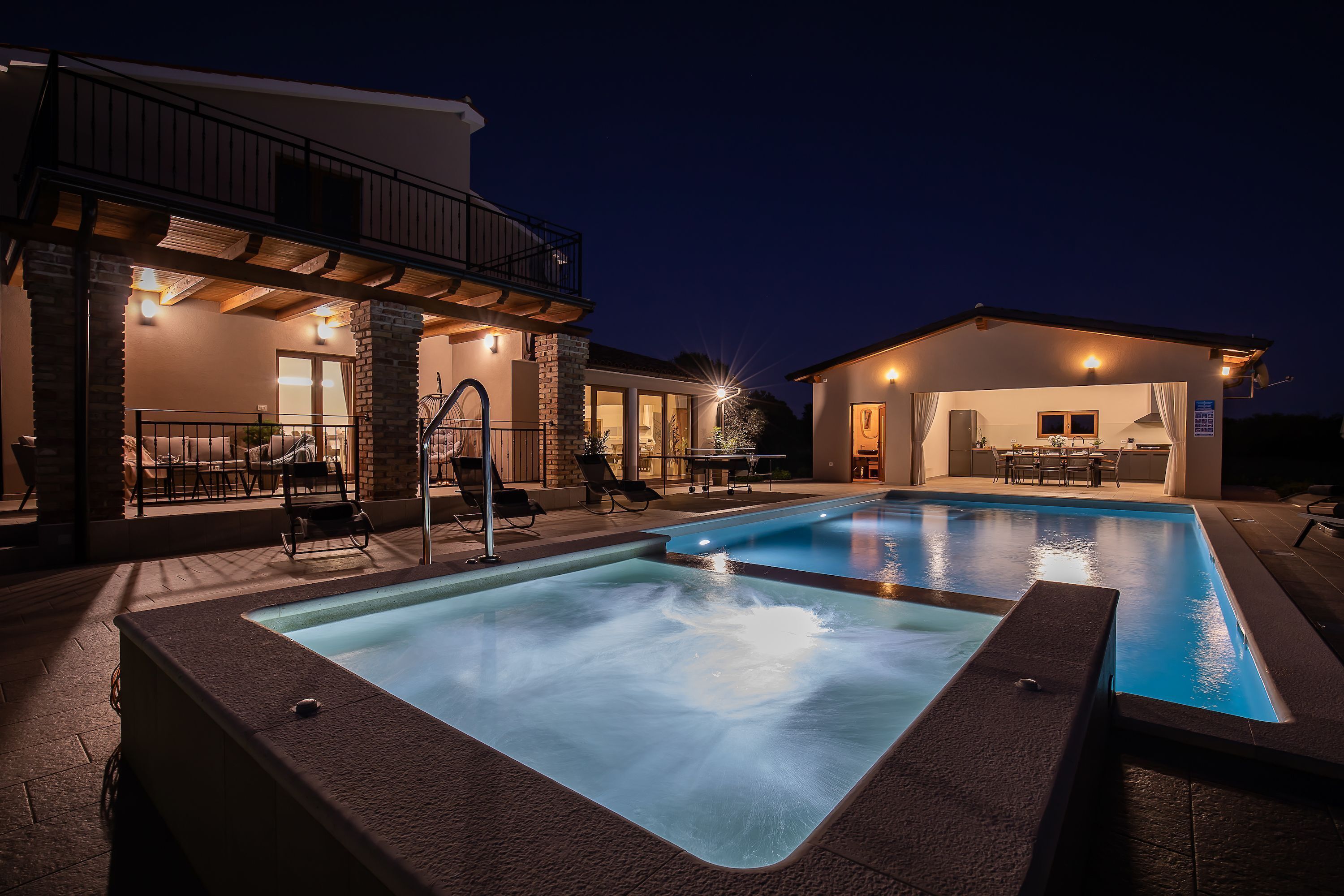 Una piscina con hidromasaje, mobiliario exterior y un patio cubierto.