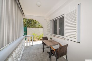 A balcony with a table and chairs, a potted plant, and a view of greenery. - Family in Sukosan With 2 Bedrooms and 1 Bathrooms (Sukosan)