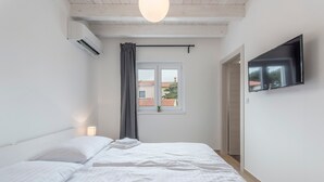 A bedroom with a bed, a TV mounted on the wall, a window with curtains, and an air conditioning unit. - Oliva in Premantura With 6 Bedrooms and 6 Bathrooms (Medulin)