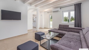 A modern living room with a sectional sofa, a glass coffee table, and a flat-screen TV mounted on the wall. - Oliva in Premantura With 6 Bedrooms and 6 Bathrooms (Medulin)