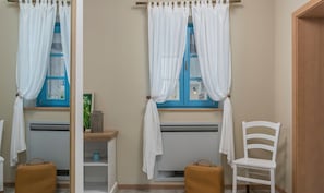Una habitación con ventana, una silla, una mesa y una maleta.