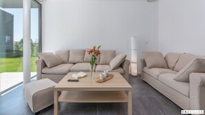 Ein modernes Wohnzimmer mit einer beigefarbenen Sofagarnitur, einem Holztisch und einer Blumenvase.