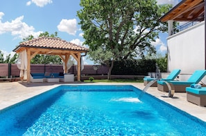 A swimming pool with a pergola and lounge chairs, surrounded by a fence and trees. - Loki in Vi Inada With 4 Bedrooms and 4 Bathrooms (Vizinada)