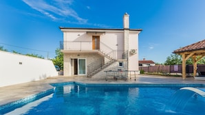 A swimming pool with a stone deck, a small staircase leading to a balcony, and a wooden pergola in the background. - Loki in Vi Inada With 4 Bedrooms and 4 Bathrooms (Vizinada)