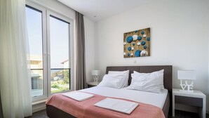 A hotel room with a bed, a nightstand, a painting, and a view of the outdoors. - Acadia D in Slatine With 6 Bedrooms and 3 Bathrooms (Split)