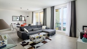 A modern living room with a sectional sofa, a glass coffee table, and a dining area with a white table and chairs. - Acadia D in Slatine With 6 Bedrooms and 3 Bathrooms (Split)