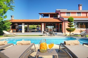 Ein Poolbereich mit Liegestühlen, einer Karaffe und Gläsern.