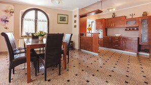 A dining area with a table and chairs, a kitchen with wooden cabinets, and a tiled floor. - Ines in Pula With 5 Bedrooms and 1 Bathrooms (Pula)