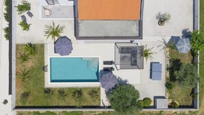 Ein Luftbild eines Grundstücks mit Swimmingpool, Sitzgelegenheiten im Freien und einer überdachten Terrasse.