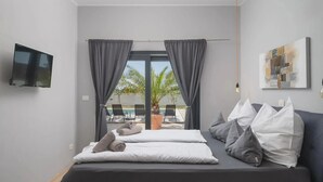 Ein modernes Schlafzimmer mit Bett, Fernseher und Blick auf einen Außenpool.