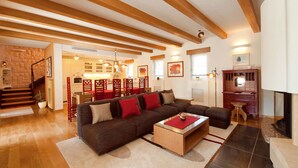 A spacious living room with a large sectional sofa, a coffee table, and a fireplace. There is a staircase leading to an upper level, and a kitchen area is visible in the background. - Vlastelini I in Labin (Labin)