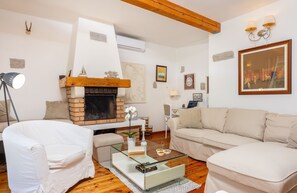 A living room with a fireplace, white sofas, and a glass coffee table. - Tribalj in Tribalj With 3 Bedrooms and 3 Bathrooms (Vinodol)